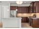 A kitchen with stainless steel appliances, an island, tile floors, and dark wood cabinets at 11415 Fort Lauderdale Pl, Venice, FL 34293