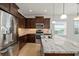 Modern kitchen featuring stainless steel appliances, granite countertops, and elegant dark wood cabinetry at 11415 Fort Lauderdale Pl, Venice, FL 34293