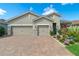 Charming home with a three-car garage, lush landscaping, and a beautifully paved driveway and walkway at 11910 Alessandro Ln, Venice, FL 34293