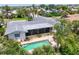Aerial shot of backyard showcasing a screened lanai, pool, mature tropical foliage, and lush flowers at 1220 Lakeside Dr, Venice, FL 34293