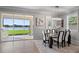 Dining area with a modern table, chandelier, and sliding glass doors leading to an outdoor grill and lake view at 12637 Promenade Estates Blvd, Sarasota, FL 34238