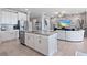 Open concept kitchen and living room with white kitchen island, stainless appliances, and stone accent wall at 12637 Promenade Estates Blvd, Sarasota, FL 34238