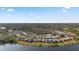 Panoramic aerial view showcasing a residential community near a lake, surrounded by lush greenery and clear skies at 12679 Sagewood Dr, Venice, FL 34293
