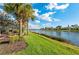 Well-manicured backyard with a serene lake view, complemented by palm trees and vibrant landscaping at 13309 Ipolita St, Venice, FL 34293