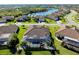 Aerial view of a beautiful home with a screened pool area, lush landscaping, and a serene lake nearby at 13652 Classico Ct, Venice, FL 34293