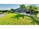 Expansive backyard with lush green lawn and mature palm trees, complemented by a screened lanai and lake view at 13652 Classico Ct, Venice, FL 34293