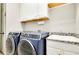 Bright laundry room featuring front loading washer and dryer, upper cabinets, and granite countertop sink at 13652 Classico Ct, Venice, FL 34293