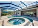 Screened in pool with jacuzzi overlooking a serene lake with comfortable outdoor lounge furniture at 13652 Classico Ct, Venice, FL 34293