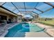 A clear swimming pool inside a screened in lanai overlooks green spaces on a sunny day at 13652 Classico Ct, Venice, FL 34293