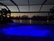 Stunning backyard pool and hot tub with blue LED lights overlooking serene lake at twilight at 13652 Classico Ct, Venice, FL 34293