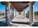 Beautiful walkway with white columns and pergola, surrounded by lush landscaping on a sunny day at 13652 Classico Ct, Venice, FL 34293