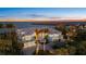 Aerial view of a luxurious waterfront home with beautifully landscaped grounds and stunning ocean views at dusk at 14 Grouper Hole Dr, Boca Grande, FL 33921