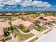 Beautiful aerial view of homes with barrel tile roofs and landscaped yards near a golf course and lake at 142 Palazzo Ct, North Venice, FL 34275