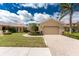 Attractive exterior view with manicured lawn, brick driveway, tropical landscaping, and a neutral paint scheme at 142 Palazzo Ct, North Venice, FL 34275