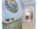 Hallway features light blue walls, neutral tile flooring, and a decorative gold-framed mirror over a buffet table at 142 Palazzo Ct, North Venice, FL 34275