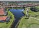 Beautiful aerial view of a home backing onto a pond, with a golf course nearby and red tile roofs on the houses at 162 Treviso Ct, North Venice, FL 34275