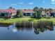 View of backyard, showing the lake, landscaping, and lanai of a well-maintained house with red tile roof at 162 Treviso Ct, North Venice, FL 34275