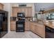 Modern kitchen featuring granite countertops, tan cabinets, stainless steel sink and black appliances at 162 Treviso Ct, North Venice, FL 34275
