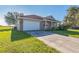 Tan single-story home featuring a two-car garage, tile roof and well maintained lawn at 17370 Cape Horn Blvd, Punta Gorda, FL 33955