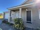 Front entrance of home featuring a covered porch, dark door, and manicured plants at 17370 Cape Horn Blvd, Punta Gorda, FL 33955
