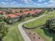 Aerial view of residences with terracotta roofs adjacent to golf course and waterway in a tropical setting at 174 Treviso Ct, North Venice, FL 34275
