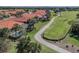 Scenic aerial view of homes with red tile roofs next to a golf course, and a walking path at 174 Treviso Ct, North Venice, FL 34275