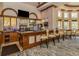Spacious bar area with dark wood, stools, bar top, TV and large selection of beverages at 174 Treviso Ct, North Venice, FL 34275