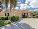 Inviting single-story home with a terracotta tile roof, manicured bushes, and an attached two-car garage at 174 Treviso Ct, North Venice, FL 34275