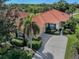 Charming single-story home featuring a terracotta tile roof, lush landscaping, and a concrete driveway at 174 Treviso Ct, North Venice, FL 34275