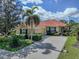 Lovely one-story home with a terracotta roof, lush landscaping, and a paved driveway leading to the garage at 174 Treviso Ct, North Venice, FL 34275