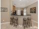 Modern kitchen area with a breakfast bar featuring stylish woven stools and sleek countertops at 174 Treviso Ct, North Venice, FL 34275