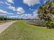Scenic walking path by a pond with lush green grass, bushes, and single-Gathering homes in the distance at 174 Treviso Ct, North Venice, FL 34275