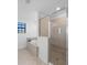 Bright bathroom featuring a glass-enclosed shower and a soaking tub with beige tile and a window with blinds at 17449 Luminous Ave, Venice, FL 34293