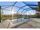 Screened-in pool and spa with brick pavers, overlooking a green expanse at 17449 Luminous Ave, Venice, FL 34293