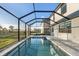 A screened-in pool area with blue water, a spa, and a patio with brick flooring at 17449 Luminous Ave, Venice, FL 34293