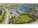 Scenic aerial view of community amenities, including tennis courts, playground, and parking areas by a beautiful lake at 19651 Quisto St, Venice, FL 34293