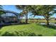 Landscaped backyard features a screened-in lanai, lush green lawn, mature trees, and a pond view at 19651 Quisto St, Venice, FL 34293
