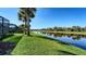 Picture of a beautifully landscaped backyard with lush lawn, palm trees, pond, and screened-in lanai at 19651 Quisto St, Venice, FL 34293