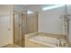 Bathroom featuring a glass-enclosed shower, soaking tub, and neutral tile at 19651 Quisto St, Venice, FL 34293