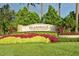 Beautifully landscaped Islandwalk community entrance with vibrant flowers, palm trees, and a clear blue sky at 19651 Quisto St, Venice, FL 34293