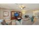 Living room features a large tv, entertainment center, sofa, sitting chairs, and ceiling fan at 19651 Quisto St, Venice, FL 34293