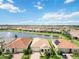 A scenic aerial view of a lakeside community showcasing homes with terracotta roofs and lush landscaping at 20389 Minuet Pl, Venice, FL 34293