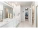 Bright bathroom features a double sink vanity with white cabinets, decorative accents and access to a walk-in closet at 20389 Minuet Pl, Venice, FL 34293