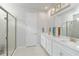 Bright bathroom featuring double sink vanity with framed mirror, white cabinets and a glass enclosed shower at 20389 Minuet Pl, Venice, FL 34293