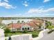 Lovely stone clubhouse with a red tile roof, lush landscaping, and a tranquil lake view, perfect for relaxation and leisure at 20389 Minuet Pl, Venice, FL 34293