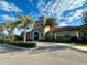 Charming stone clubhouse with a tile roof, surrounded by lush greenery and palm trees, creating a welcoming community space at 20389 Minuet Pl, Venice, FL 34293