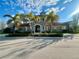 Beautiful stone clubhouse with a tile roof, palm trees, and a manicured lawn, offering a welcoming community atmosphere at 20389 Minuet Pl, Venice, FL 34293