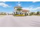 Elegant community entrance with stone accents, a tiled roof, and lush landscaping with vibrant yellow flowers at 20389 Minuet Pl, Venice, FL 34293