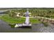 Aerial shot of a dock overlooking the lake surrounded by lush greenery and clear skies with landscaped walking paths at 20389 Minuet Pl, Venice, FL 34293