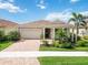 Inviting single-story home with a tile roof, attached garage, and mature tropical landscaping at 20389 Minuet Pl, Venice, FL 34293